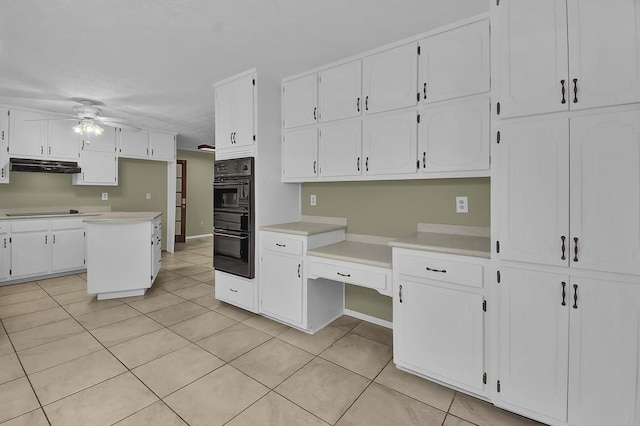 kitchen featuring light tile patterned floors, ceiling fan, white cabinetry, a center island, and black appliances