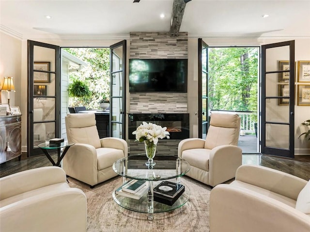 living room featuring a tile fireplace, a wealth of natural light, hardwood / wood-style floors, and beamed ceiling