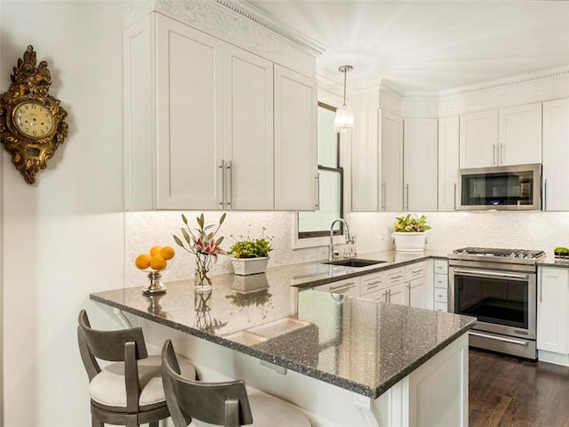 kitchen with decorative light fixtures, sink, kitchen peninsula, and stainless steel appliances