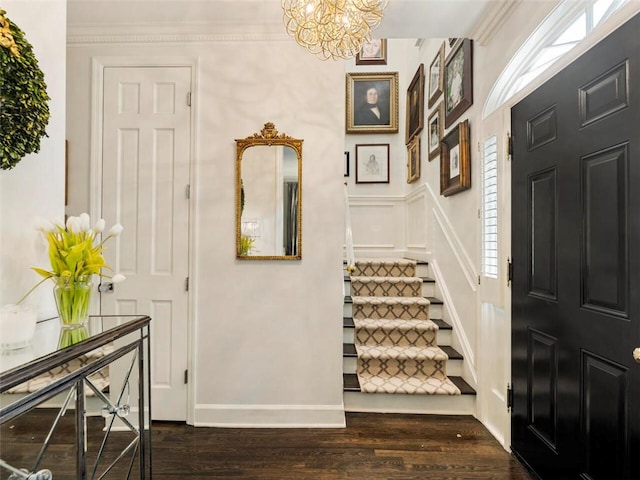 foyer entrance with ornamental molding, dark wood-type flooring, and an inviting chandelier