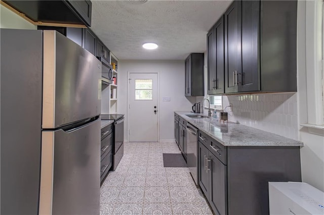 kitchen with tasteful backsplash, appliances with stainless steel finishes, a textured ceiling, light tile patterned floors, and sink