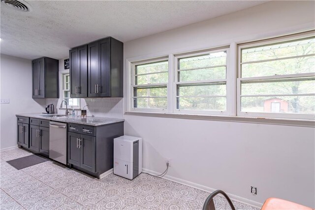 kitchen with light stone countertops, a textured ceiling, sink, and dishwasher