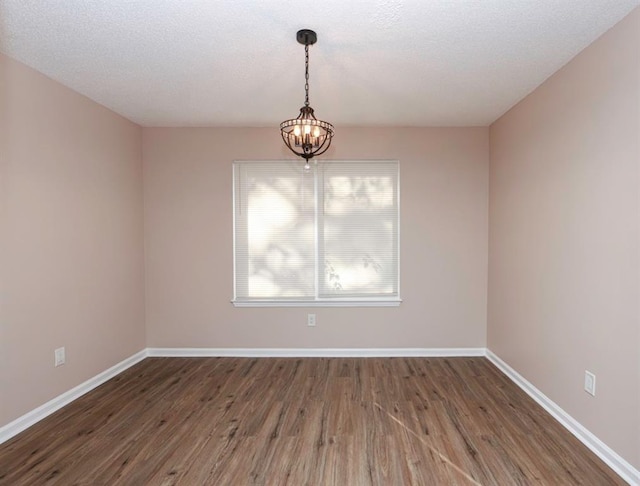 unfurnished room with dark hardwood / wood-style floors, a textured ceiling, and a chandelier