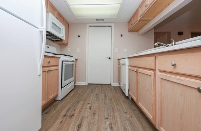 kitchen with light brown cabinetry, white appliances, and light hardwood / wood-style floors