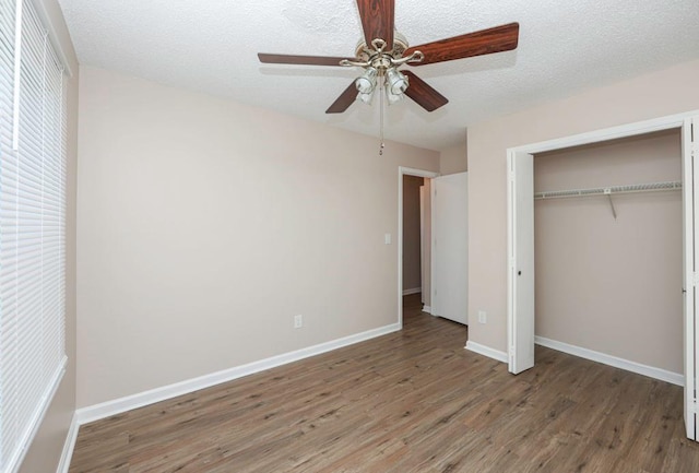 unfurnished bedroom featuring a textured ceiling, ceiling fan, dark wood-type flooring, and a closet