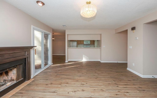 unfurnished living room with a notable chandelier, wood-type flooring, and a textured ceiling