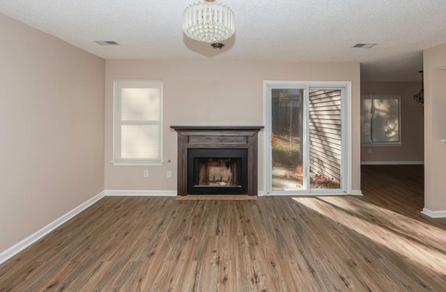 unfurnished living room featuring a textured ceiling, dark hardwood / wood-style floors, and a notable chandelier