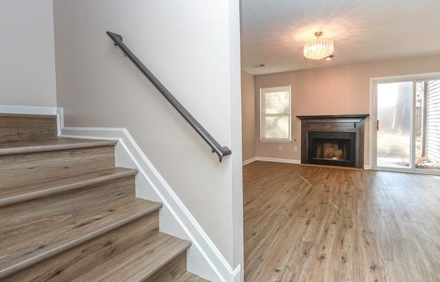 stairs with hardwood / wood-style floors and a notable chandelier