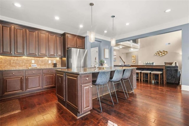 229 Primstone Way, Mcdonough, GA 30253 - kitchen featuring freestanding refrigerator, a breakfast bar area, light stone counters, an island with sink, and tasteful backsplash