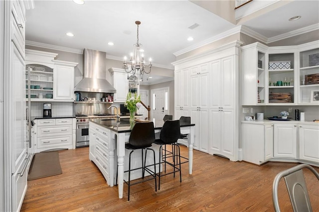 8643 Ellard Dr, Alpharetta, GA 30022 - kitchen featuring wall chimney range hood, light wood-type flooring, a chandelier, recessed lighting, and white cabinets