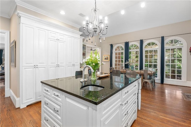 8643 Ellard Dr, Alpharetta, GA 30022 - kitchen featuring a chandelier, ornamental molding, light wood-style floors, dark stone counters, and decorative light fixtures
