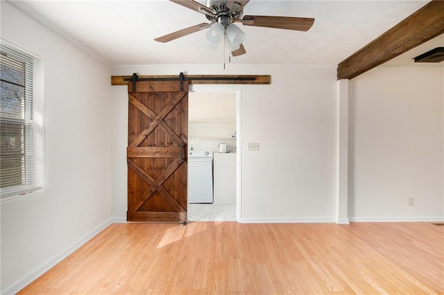 40 Kingston Dr, Comer, GA 30629 - empty room featuring a barn door, a ceiling fan, washer and clothes dryer, light wood-type flooring, and baseboards