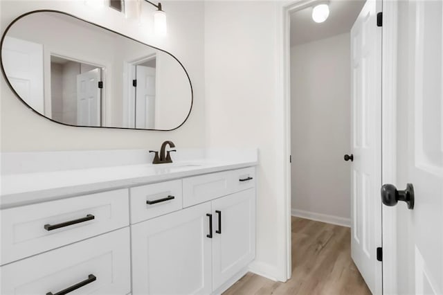 bathroom with wood finished floors, vanity, and baseboards