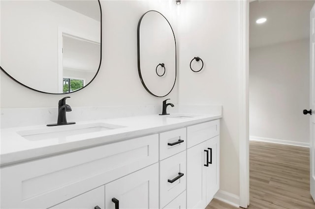 bathroom with double vanity, wood finished floors, baseboards, and recessed lighting