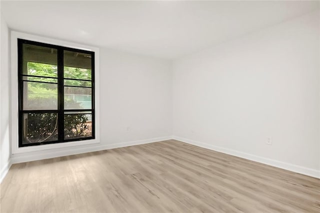 spare room featuring light wood-type flooring and baseboards