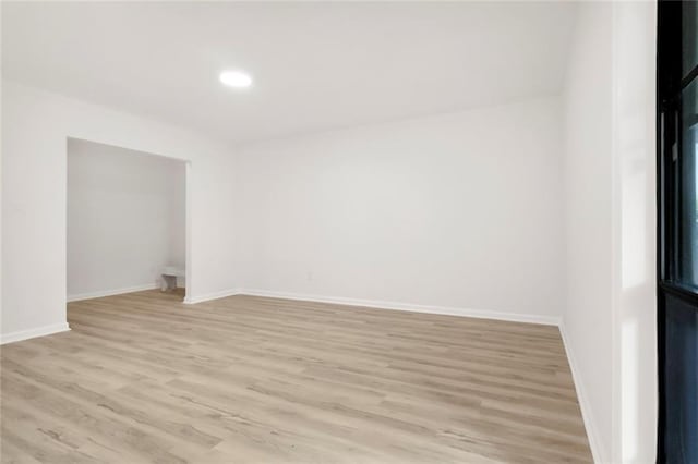 empty room with light wood-type flooring, baseboards, and recessed lighting