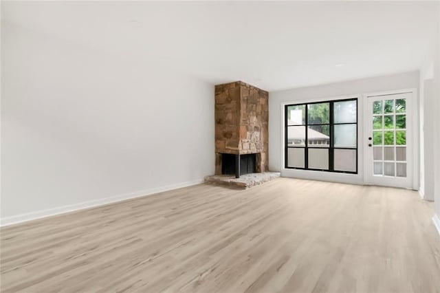 unfurnished living room with light wood finished floors, a fireplace, and baseboards