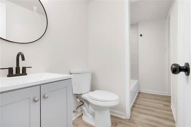 bathroom featuring toilet, wood finished floors, vanity, and baseboards