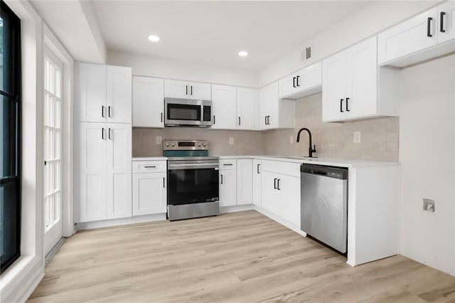 kitchen with stainless steel appliances, a sink, light countertops, backsplash, and recessed lighting