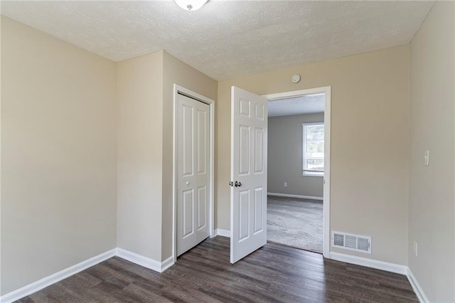 unfurnished room featuring a textured ceiling and dark wood-type flooring