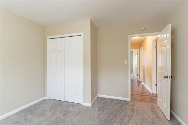 unfurnished bedroom with light colored carpet and a closet