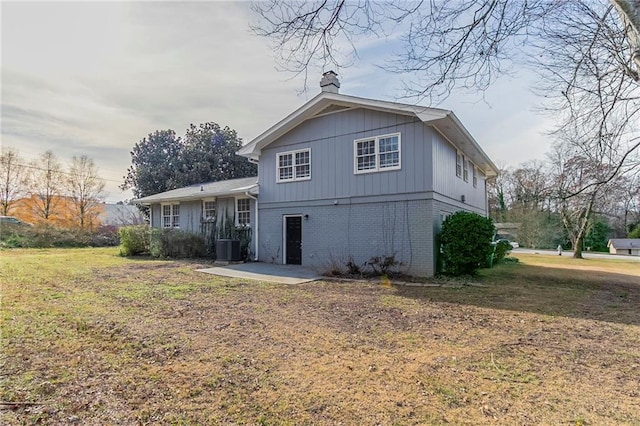 rear view of house with central AC and a yard