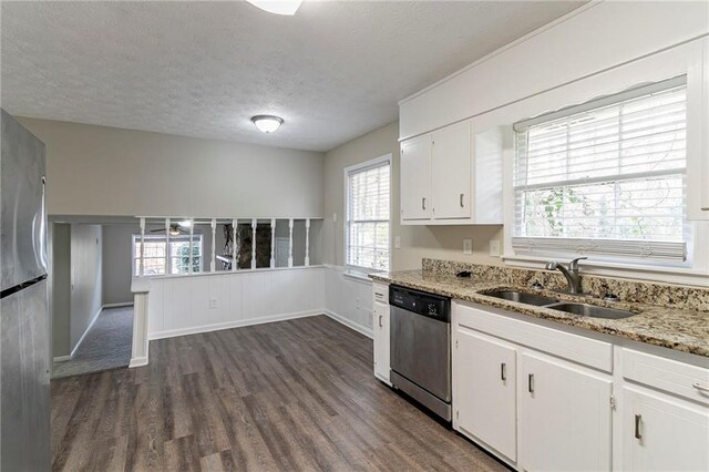 kitchen with appliances with stainless steel finishes, a textured ceiling, dark wood-type flooring, sink, and white cabinetry