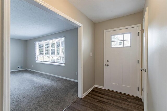 foyer featuring plenty of natural light and dark colored carpet