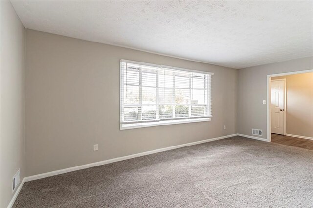 carpeted empty room featuring a textured ceiling