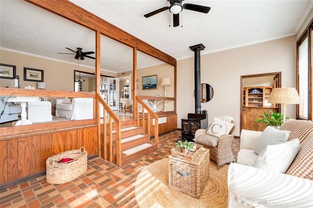 living room with brick floor, a wood stove, ornamental molding, and beamed ceiling