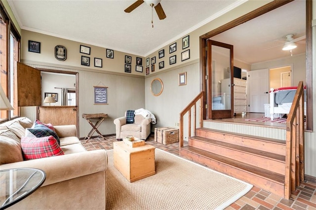 living area featuring brick floor, ceiling fan, and ornamental molding