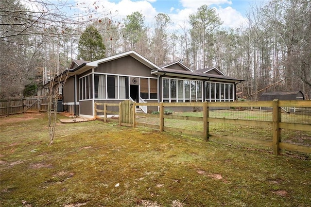 view of front of house with a fenced backyard, central AC, a sunroom, a gate, and a front lawn