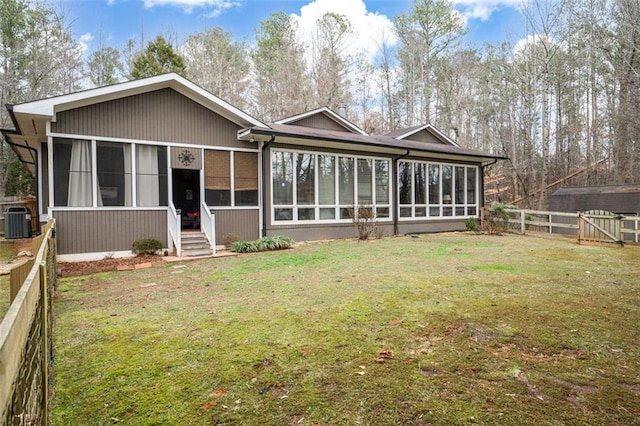 back of property with cooling unit, a sunroom, a fenced backyard, and a lawn