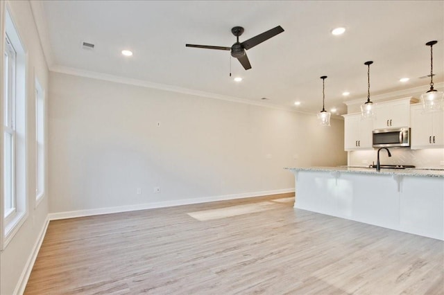 kitchen featuring pendant lighting, a breakfast bar, light stone countertops, light wood-type flooring, and white cabinetry