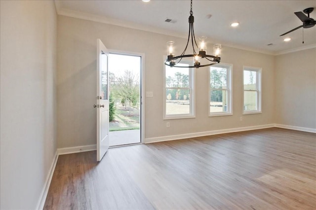 interior space with ceiling fan with notable chandelier, a healthy amount of sunlight, wood-type flooring, and ornamental molding