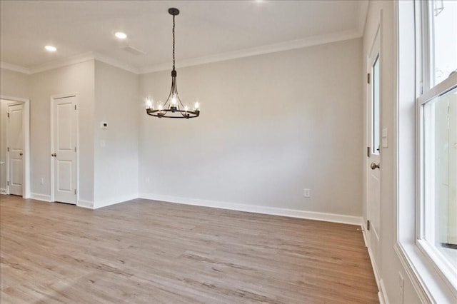 spare room with a chandelier, hardwood / wood-style flooring, and ornamental molding