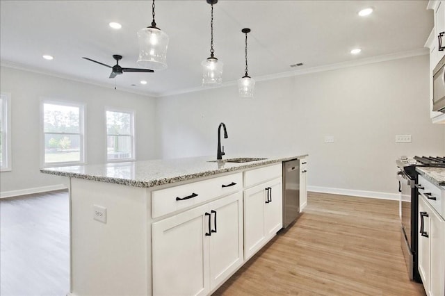 kitchen featuring light stone countertops, stainless steel appliances, sink, a center island with sink, and white cabinets