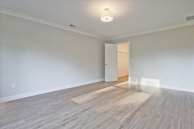 spare room featuring light wood-type flooring and ornamental molding