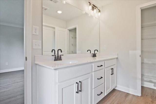 bathroom featuring wood-type flooring, vanity, and crown molding