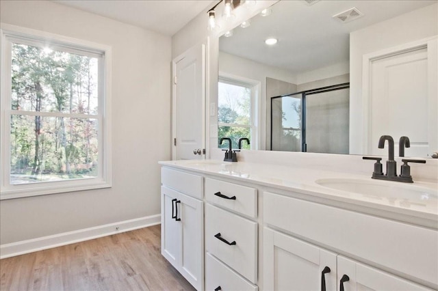 bathroom featuring a wealth of natural light, hardwood / wood-style floors, vanity, and a shower with shower door