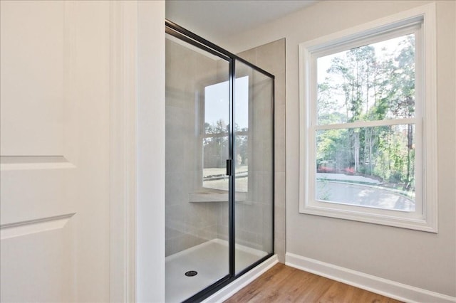 bathroom with hardwood / wood-style floors and a shower with shower door