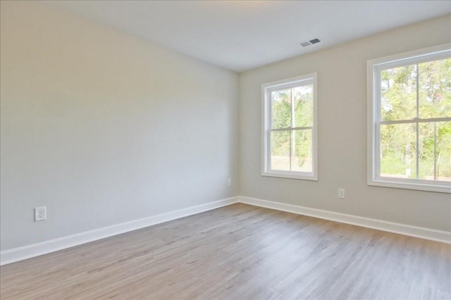 spare room with plenty of natural light and light hardwood / wood-style floors