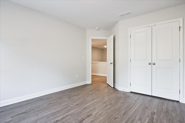 unfurnished bedroom featuring dark hardwood / wood-style flooring and a closet