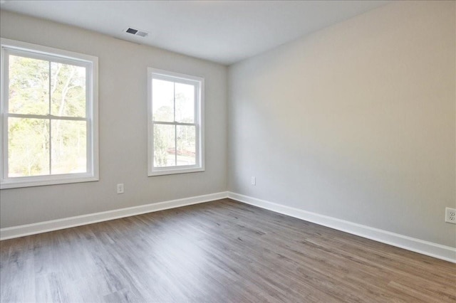 empty room featuring a healthy amount of sunlight and dark wood-type flooring