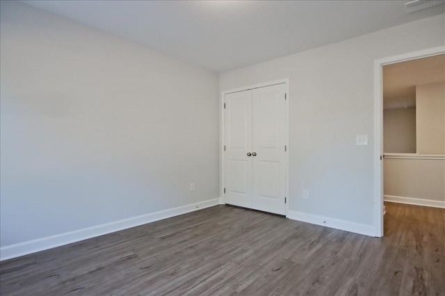 unfurnished bedroom with a closet and dark hardwood / wood-style floors