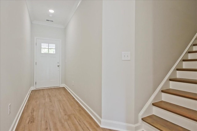 entryway with light wood-type flooring and crown molding