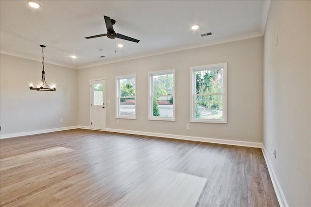 empty room with hardwood / wood-style flooring, ceiling fan with notable chandelier, and ornamental molding