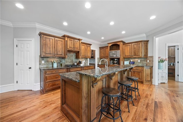 2517 Stone Manor Dr, Buford, GA 30519 - kitchen with stainless steel microwave, brown cabinets, a breakfast bar, light wood-type flooring, and ornamental molding