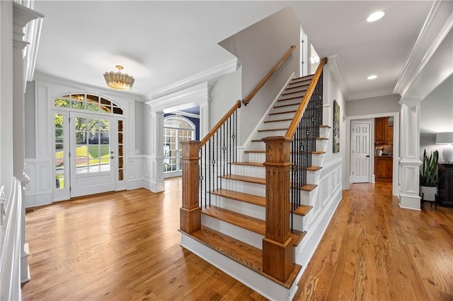 2517 Stone Manor Dr, Buford, GA 30519 - foyer entrance featuring ornate columns, a decorative wall, crown molding, stairs, and light wood finished floors