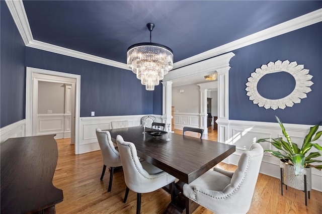 2517 Stone Manor Dr, Buford, GA 30519 - dining area featuring decorative columns, a chandelier, crown molding, a wainscoted wall, and a decorative wall